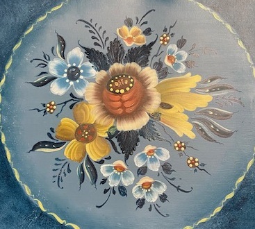 Painted bouquet of blue, gold, and rust flowers on a soft blue round